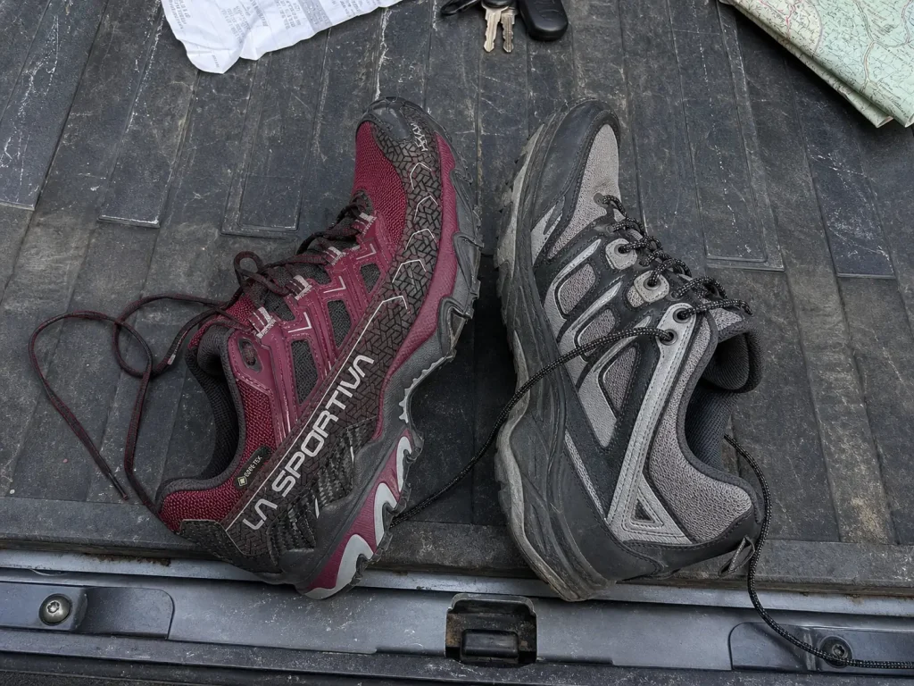 Two hiking shoes side by side on a tailgate showing the width difference in the forefoot