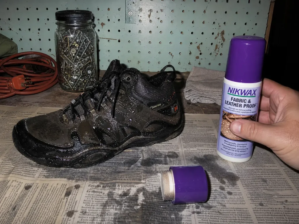 Reproofing treatment applied to a damp hiking shoe on a garage bench to restore DWR and breathability