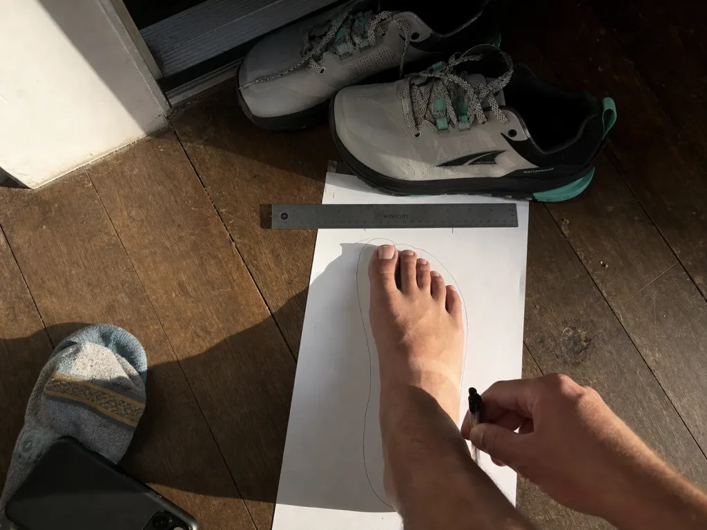 Tracing a foot on paper to measure width before buying hiking shoes for wide feet