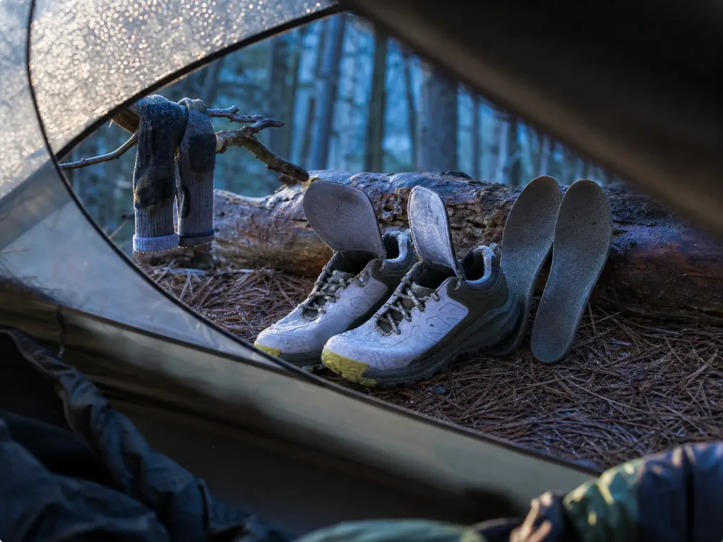 Waterproof hiking shoes airing out at camp with insoles removed after getting soaked