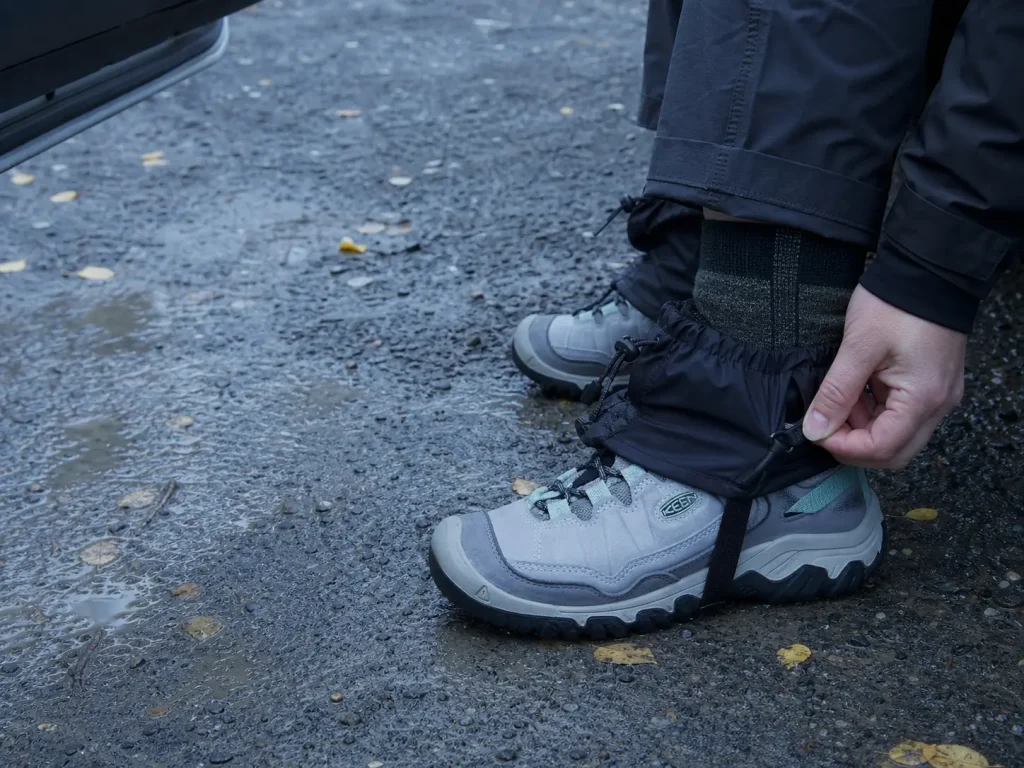 Low gaiters and merino socks fitted over low-cut hiking shoes at a trailhead in cool weather