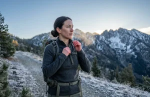 Best Base Layers for Cold Weather Hiking 2026 Hiker wearing a merino wool base layer at cold alpine trailhead in early morning frost
