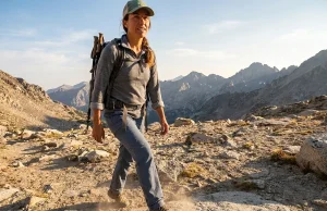 7 Best Hiking Shoes for Wide Feet Women 2026 Woman with wide feet hiking on rocky trail in supportive low hiking shoes during golden hour