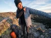 Best Lightweight Down Jackets Worth Buying for Hiking Hiker pausing at ridgeline to pull on lightweight down jacket in cold alpine morning light