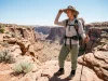 Desert Hiking Clothes Most Hikers Get Wrong Female hiker evaluating choices in hiking clothes for desert heat on a canyon rim.