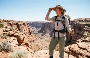 Desert Hiking Clothes Most Hikers Get Wrong Female hiker evaluating choices in hiking clothes for desert heat on a canyon rim.