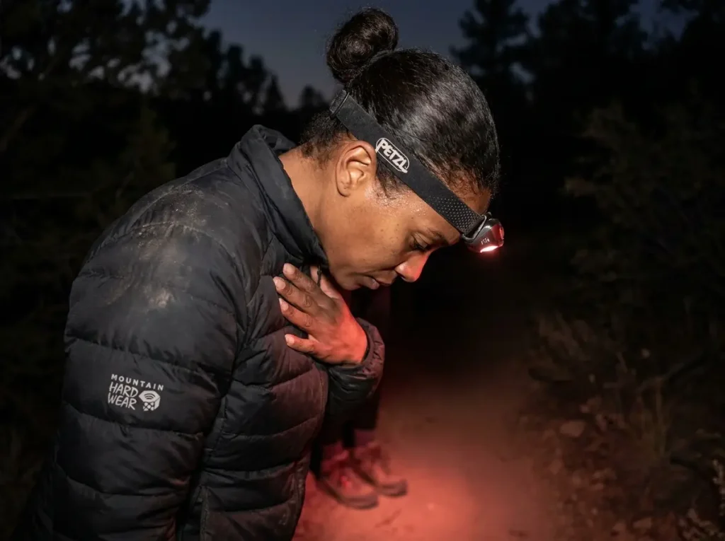 Considerate hiker pointing her red headlamp downward to respect trail etiquette.