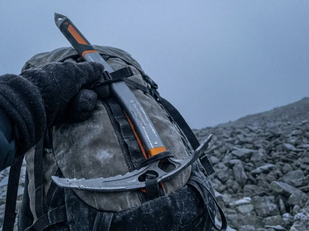 Black Diamond ice axe lashed head-down to a backpack loop with the tip pointing up