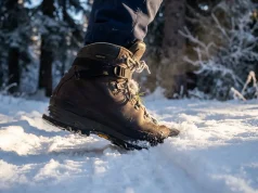 Best Insulated Winter Hiking Boots Worth the Money Close-up of an insulated winter hiking boot stepping into fresh snow on a frozen alpine trail at golden hour