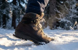 Best Insulated Winter Hiking Boots Worth the Money Close-up of an insulated winter hiking boot stepping into fresh snow on a frozen alpine trail at golden hour
