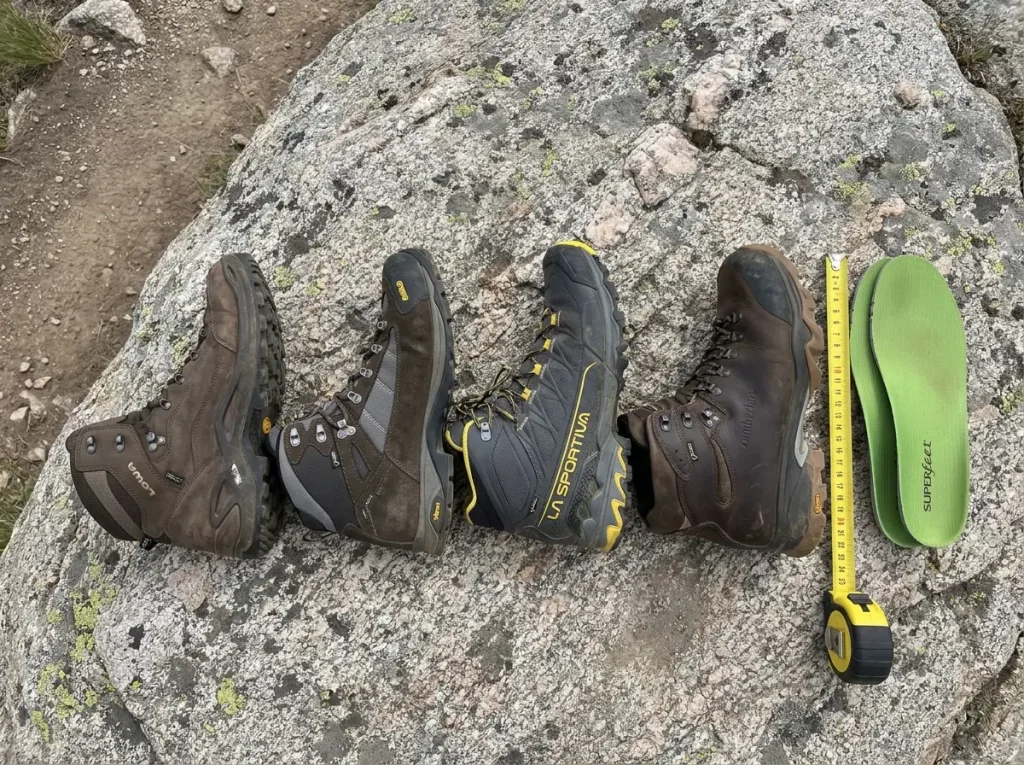 Four hiking boots from different brands lined up on granite for comparison