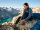 When to Size Up Hiking Footwear the Right Way Female hiker adjusting laces on Salomon hiking boots on an alpine ridge.
