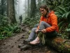 Your Sock Rotation Is Wrong and Blisters Prove It Female hiker resting on a switchback changing a wet Darn Tough sock to manage her sock rotation strategy.