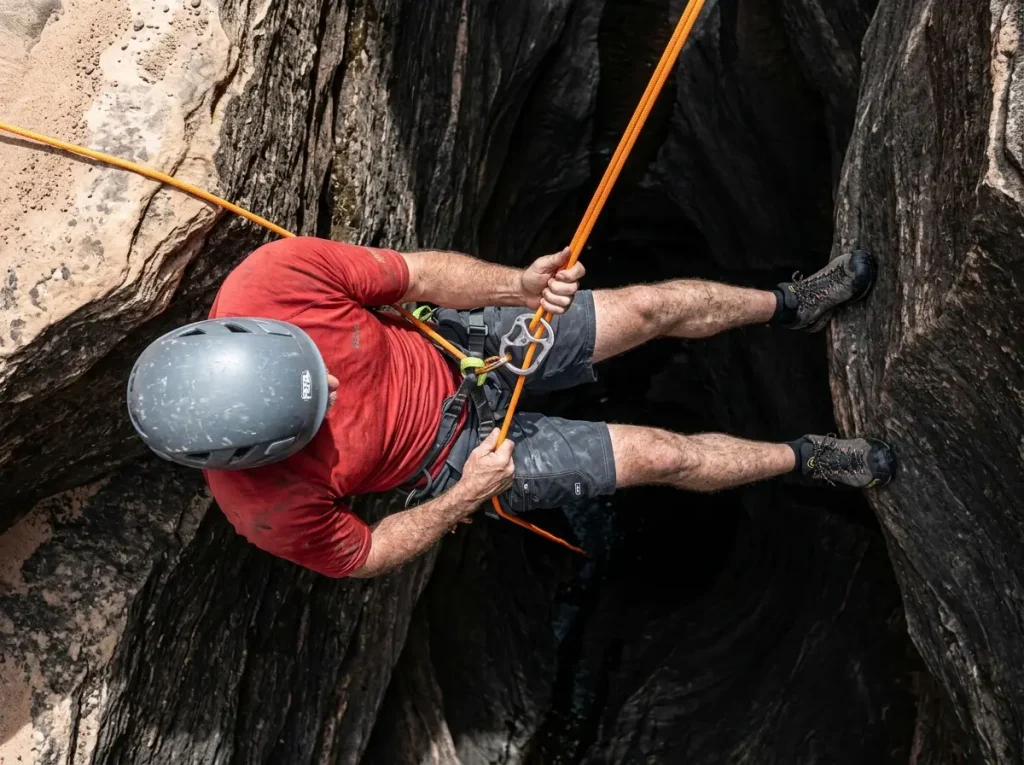 Experienced canyoneer managing a static rope rappel over a sharp edge