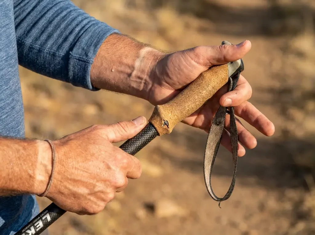 Close-up of hiker's hands mid-transfer passing single trekking pole between hands on trail