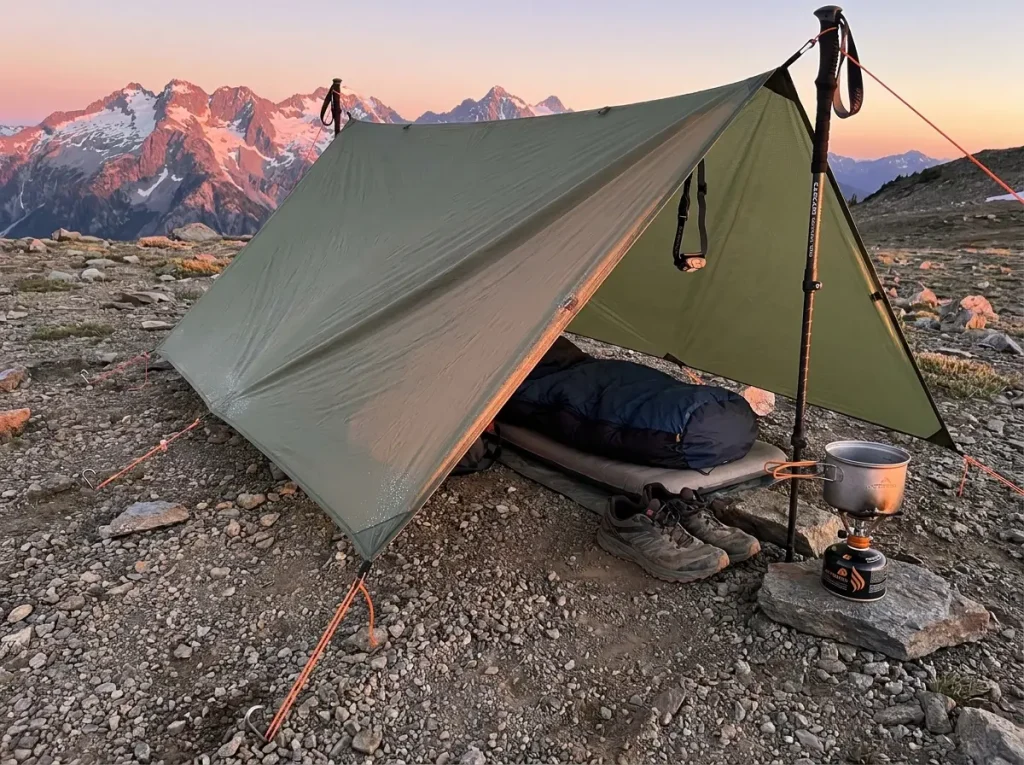 Trekking pole tarp shelter pitched using two hiking poles at a mountain campsite