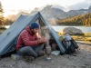 What Thru-Hikers Pick for One-Person Ultralight Tents Solo backpacker boiling water beside a pitched one-person ultralight tent at alpine dawn beside a mountain lake