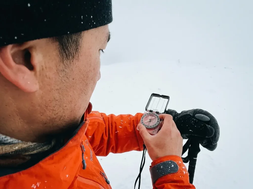 Using a Suunto compass to navigate through flat snowy whiteout conditions.
