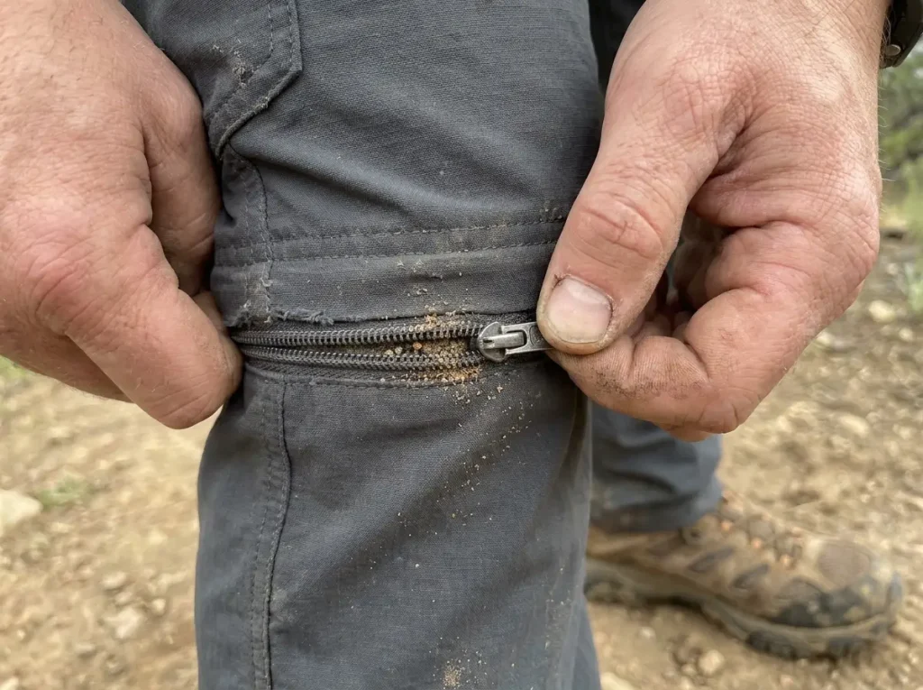 Close up of convertible hiking pants zipper mechanism showing dirt in teeth