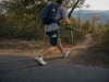 7 Road-to-Trail Shoes That Hold Up Under a Daypack Hiker in road-to-trail shoes stepping off pavement onto a dirt trail with a daypack on