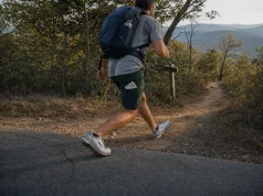 7 Road-to-Trail Shoes That Hold Up Under a Daypack Hiker in road-to-trail shoes stepping off pavement onto a dirt trail with a daypack on
