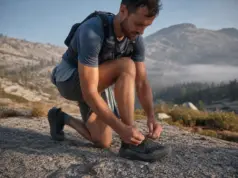 Speed Hiking Shoes vs Trail Runners What Changes Hiker retying speed hiking shoes on a granite slab before a fast alpine push