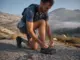 Speed Hiking Shoes vs Trail Runners What Changes Hiker retying speed hiking shoes on a granite slab before a fast alpine push