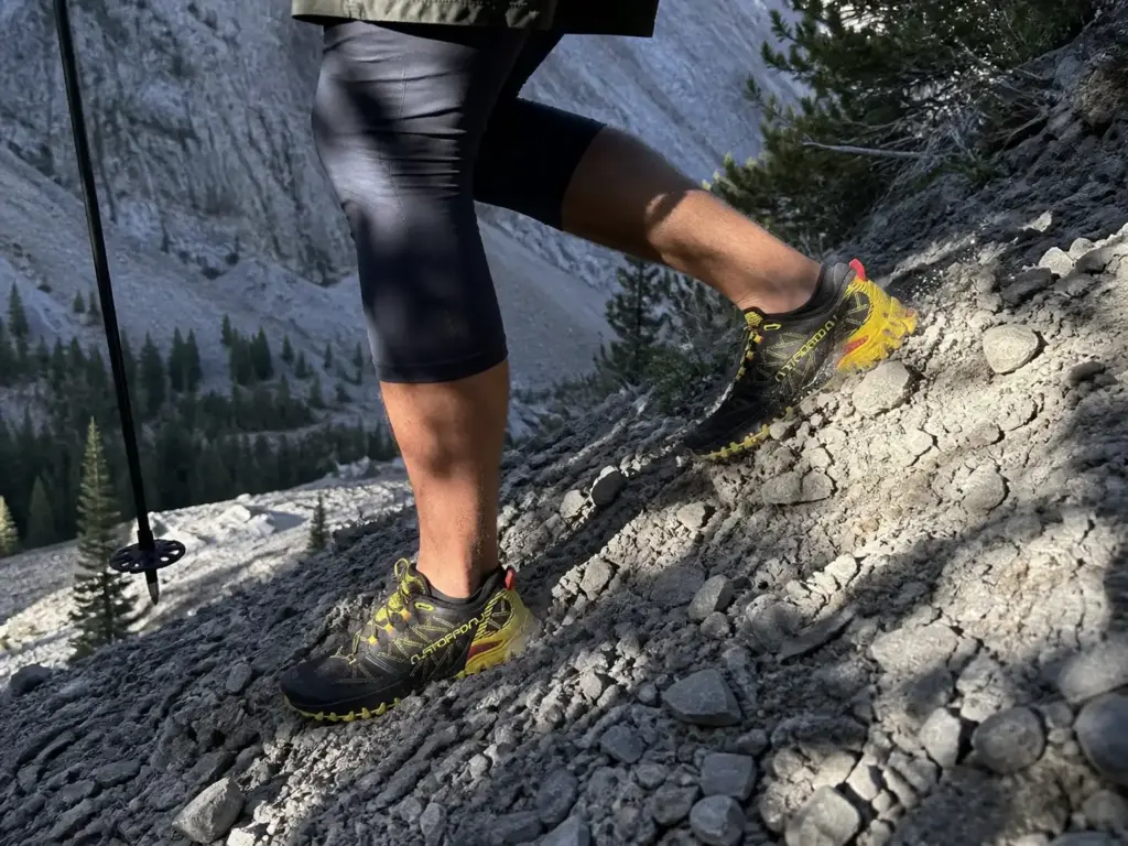 Stiff rock-plated shoe edging across loose scree on a fast off-trail traverse