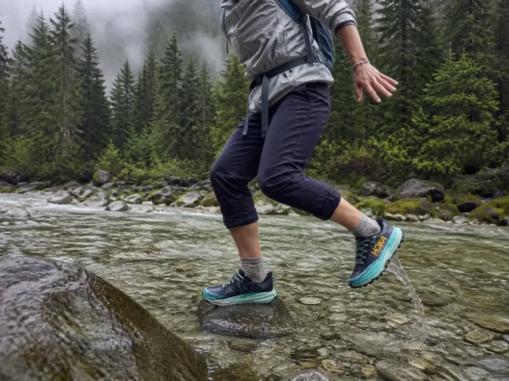 Wet mesh trail runners crossing a shallow creek on a three-season hike