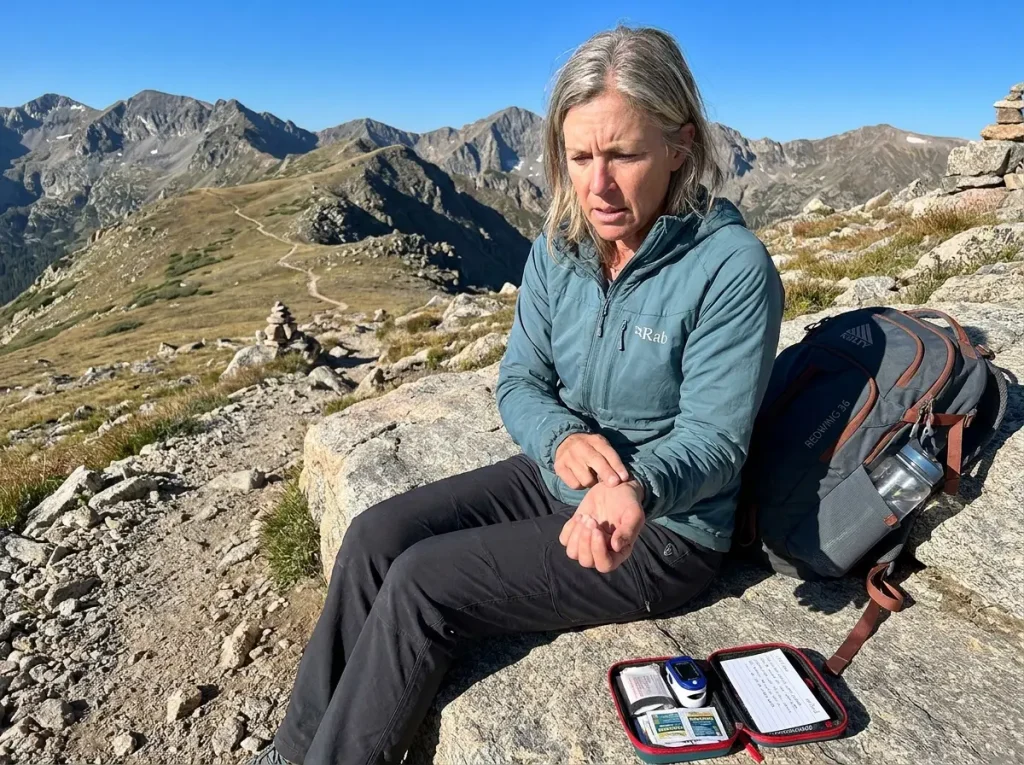 Hiker checking pulse on wrist while resting on a high mountain trail