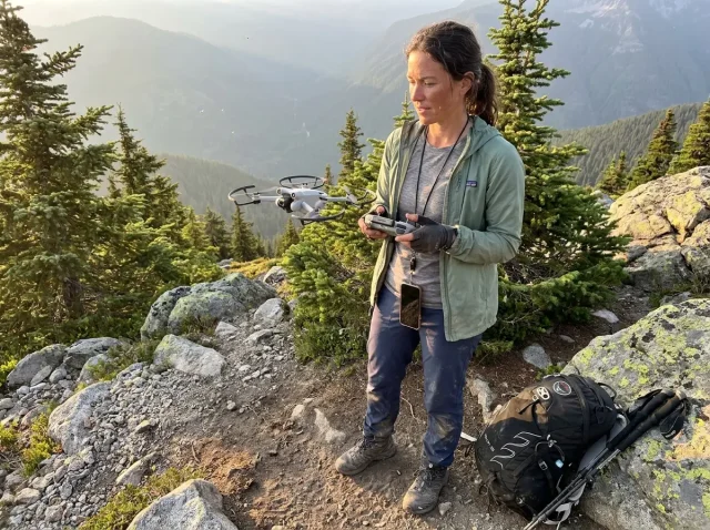 hiker-launching-drone-mountain-trail Hiker launching a small drone from a mountain trail clearing at golden hour