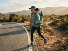 7 Hiking Shoes That Handle Road and Trail Without Flinching Hiker walking on paved road toward a dirt trail in hiking shoes at golden hour