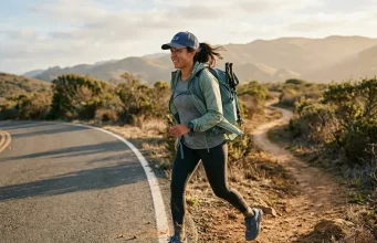 7 Hiking Shoes That Handle Road and Trail Without Flinching Hiker walking on paved road toward a dirt trail in hiking shoes at golden hour