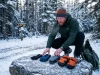 How to Choose Hiking Gloves by Temperature Range Hiker choosing between different hiking gloves spread on a snowy rock at trailhead