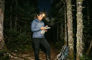 5 Night Navigation Mistakes That Get Hikers Lost Hiker checking compass by headlamp on a dark mountain trail at night