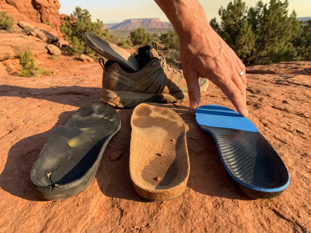 Three different orthotic insole materials laid out on a rocky trail surface
