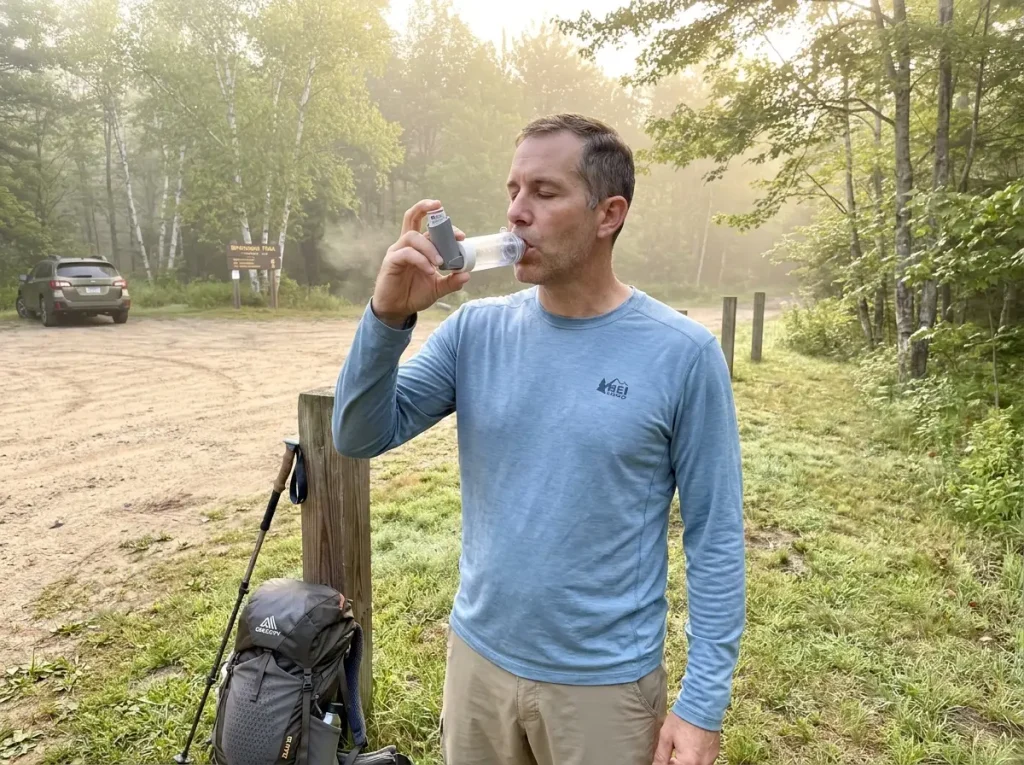 Hiker using rescue inhaler at trailhead before starting a morning hike