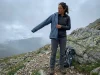 4 Rain Jacket Sizing Mistakes That Leave You Cold Hiker layering a rain jacket over fleece midlayer on a misty mountain trail