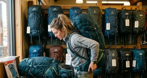 Why Buying Hiking Gear First Is a Rookie Mistake Hiker examining rental backpack fit at an outdoor gear shop counter