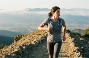 Running Vest vs Daypack and What Your Pace Decides Fast hiker in a Salomon running vest reaching for a front soft flask at dawn on a ridge trail