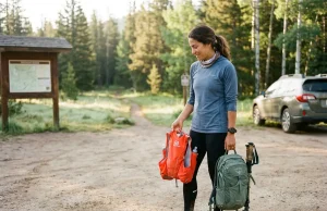Running Vest vs Daypack Which Fits Your Hiking Pace Hiker comparing running vest and daypack at a mountain trailhead before a fast day hike