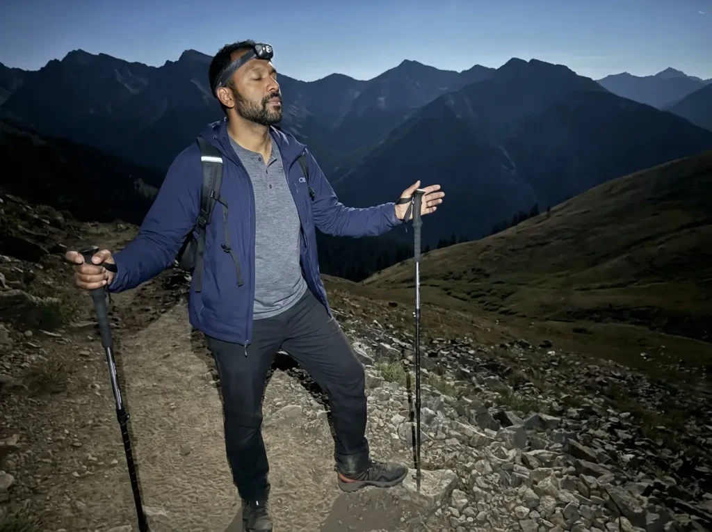 Hiker standing still on dark trail with headlamp off feeling terrain underfoot