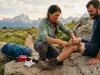 7 Steps to Apply a Tourniquet in the Backcountry Hiker applying a tourniquet on a rocky backcountry trail with mountains in the background