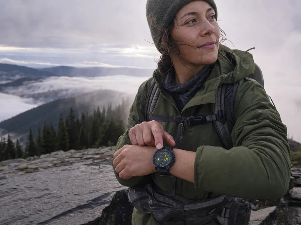 Day hiker checking a Garmin GPS watch on the wrist at a misty overlook on a cool morning