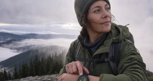 Best GPS Watch for Day Hikers and Backpackers Day hiker checking a Garmin GPS watch on the wrist at a misty overlook on a cool morning