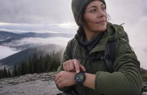 Best GPS Watch for Day Hikers and Backpackers Day hiker checking a Garmin GPS watch on the wrist at a misty overlook on a cool morning