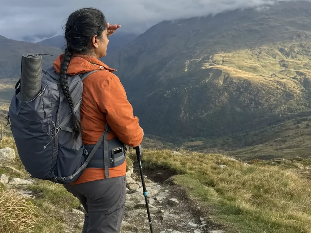 Hiker on a ridge looking up and out at the terrain with the phone put away in a pocket
