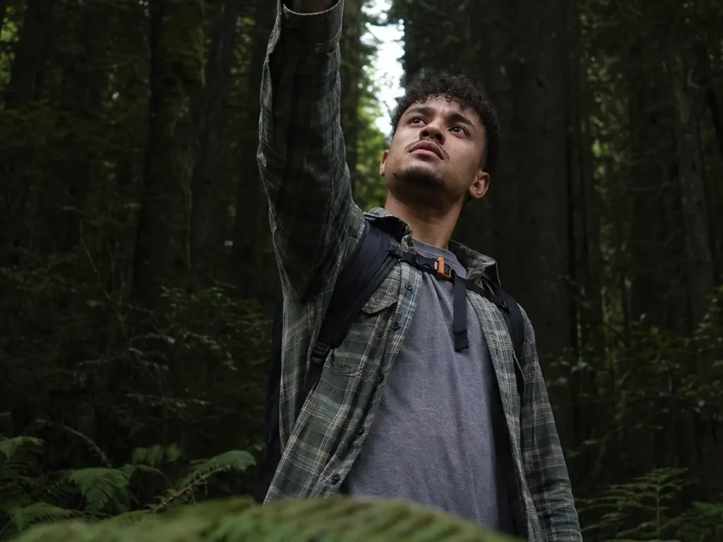Hiker holding a phone overhead in dense forest as the GPS gets a satellite fix with no cell bars