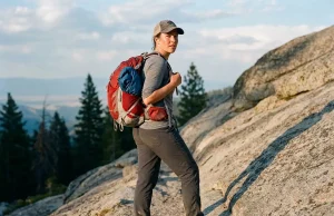 Best Hiking Daypacks for the Hike You Actually Do Hiker pausing on a granite trail wearing a 22-liter Osprey daypack at golden hour