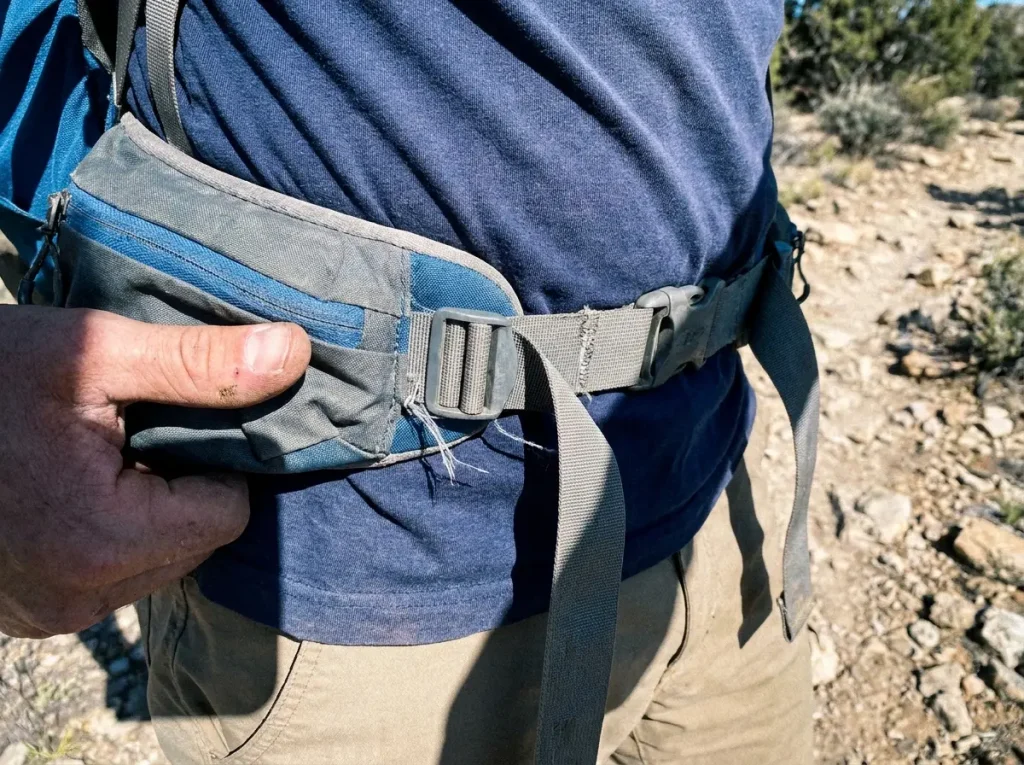 Close-up of a padded hip belt seated on a hiker's iliac crest carrying the load